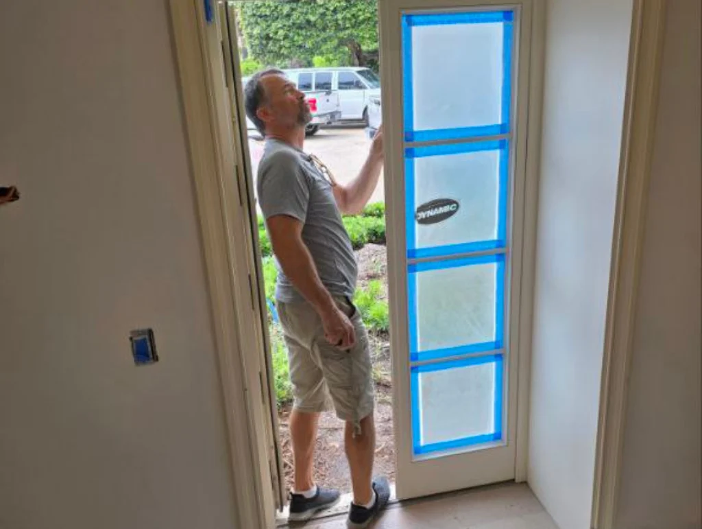 Technician handling a glass panel marked with painter's tape