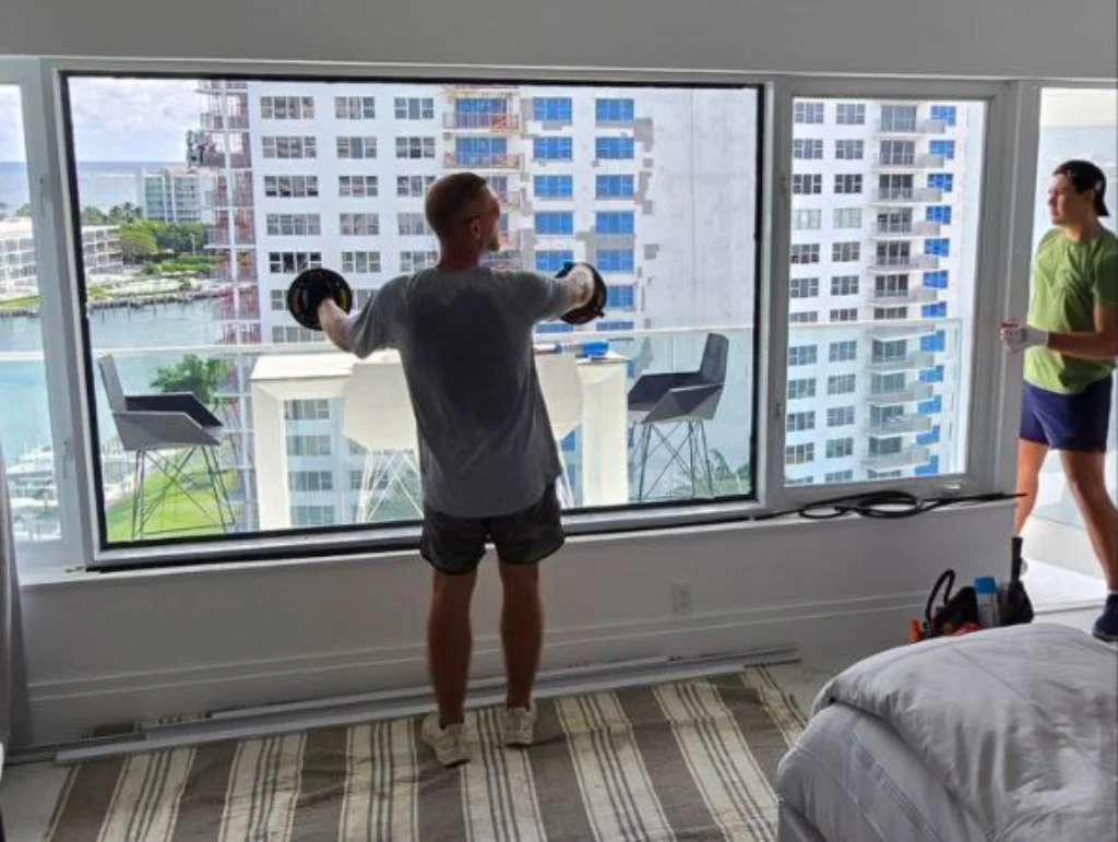 Technician cleaning a window overlooking a residential skyline