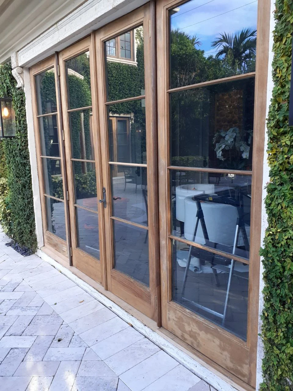 Row of wood-framed glass French doors along a stone patio
