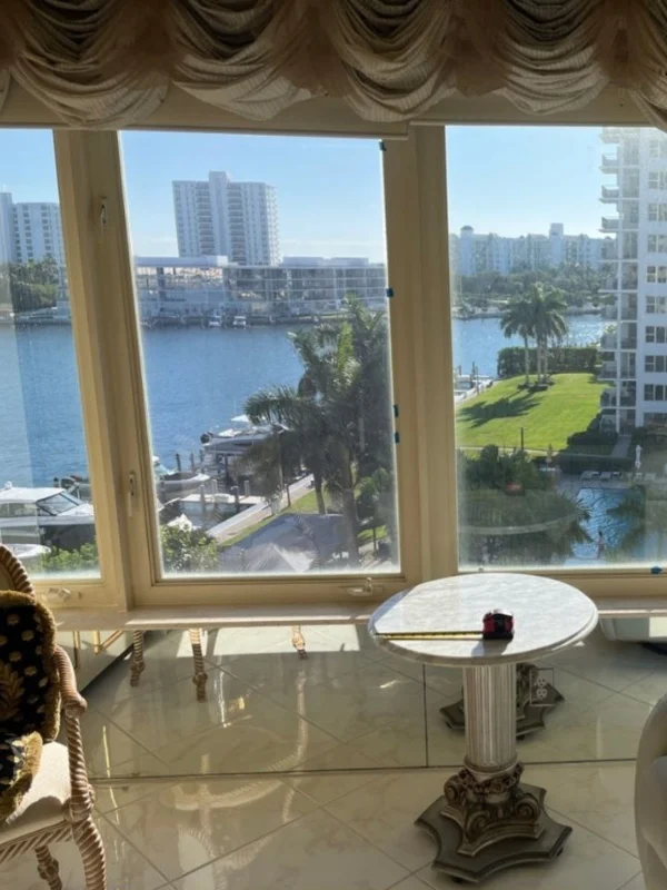 Interior window framing a marina and high-rise buildings